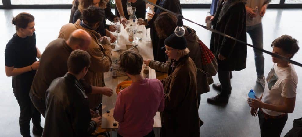 DE: Menschen die um einen Tisch stehen // EN: People standing around a table