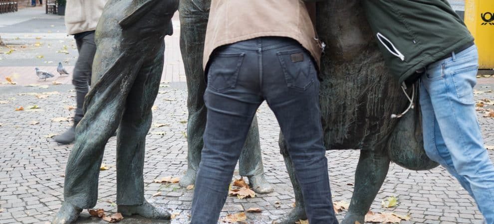 DE: Zwei Menschen, die gegen eine Statur gelehnt sind// EN: two people leaning against a stature