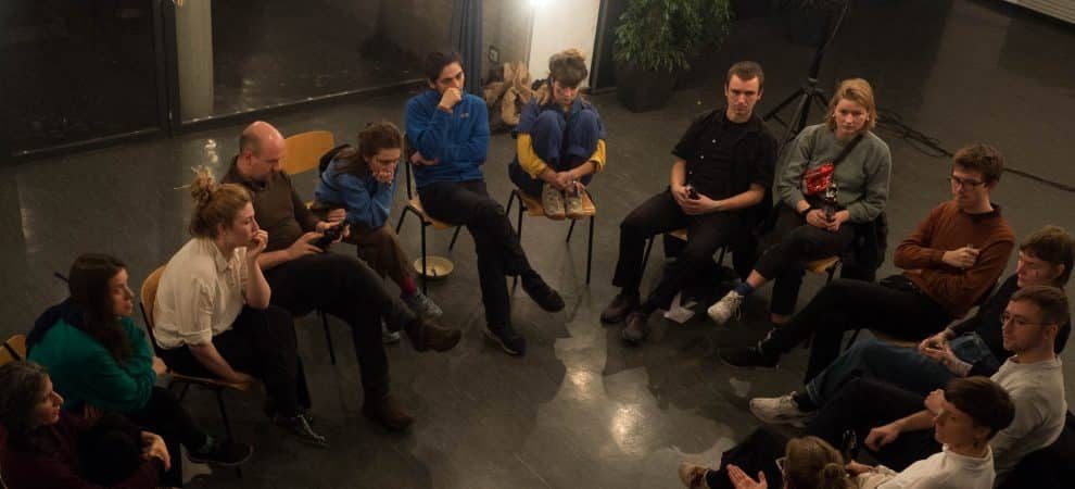 DE: Menschen sitzen im Kreis auf Stühlen und unterhalten sich//EN: People sitting in a circle on chairs and talking